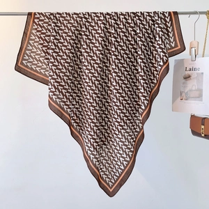 Detail of silk scarf with classic V-pattern print and contrast border on metal bar