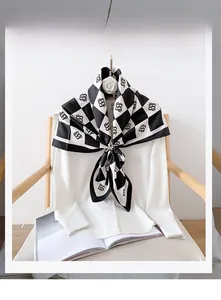 Detail of a black and white checkered polyester scarf draped over a white shirt