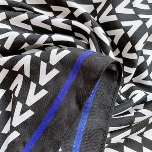 Detail of twill weave fabric scarf with black and white V-pattern and blue accents