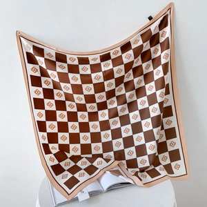 Detail of checkered silk scarf with S-logo pattern on elegant white background