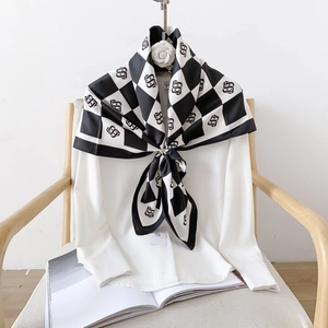 Close-up of a black and white checkerboard silk scarf with S-letter pattern on a shirt