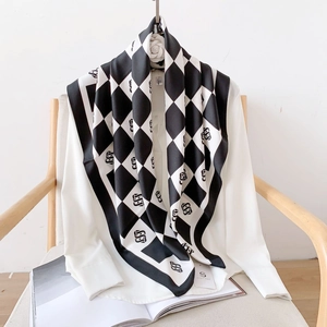 Elegant black and white checkerboard silk scarf with artistic S logo print on white shirt