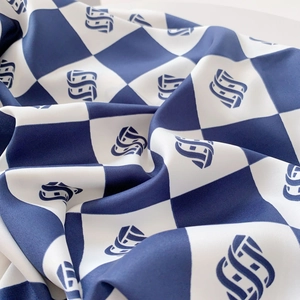 Detailed view of navy blue and white checkered twill fabric with geometric logo patterns