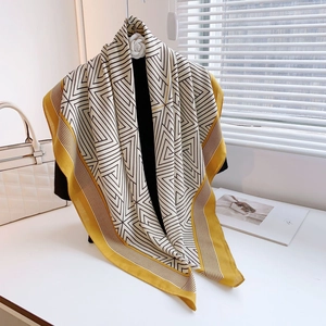 Elegant geometric print scarf with yellow borders and camellia brooch on a display
