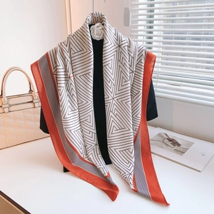 Detail of a large geometric print scarf with black stripes and orange border on a mannequin