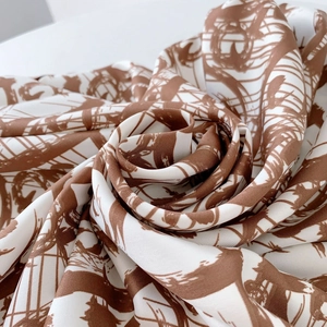 Macro detail of twill silk scarf showing rose-shaped spiral drape and abstract print