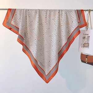 Close-up of geometric triangle pattern scarf with orange borders on a metal rack