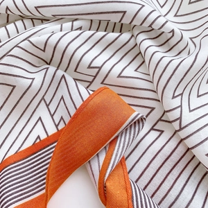 Detailed view of chevron pattern scarf with vibrant orange border and twill texture