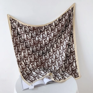 Detailed view of cream silk scarf featuring a brown repeating monogram pattern and fine hem