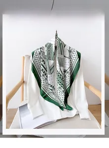 Détail d'un foulard en soie à motifs vert et blanc noué sur une chemise blanche sur une chaise