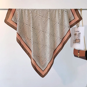 Detail of geometric pattern scarf hanging with a matching chic handbag on a clean wall