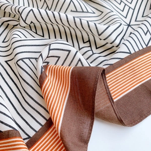 Detail of geometric line pattern silk scarf with elegant brown and orange border