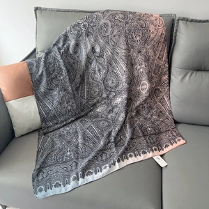 Dettaglio di una sciarpa in cotone e lino con motivo paisley drappeggiata su divano grigio