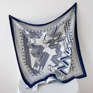 Foulard en soie bleu marine à motifs étriers géométriques drapé sur un mur blanc