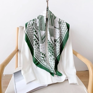 Élégant foulard en soie vert et blanc à motifs géométriques porté sur une chemise blanche