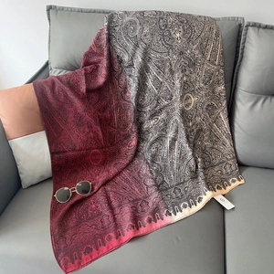 Dettaglio di scialle leggero in cotone e lino con motivo paisley su divano grigio