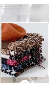 Detail of soft cashmere-like winter scarf featuring leopard animal print and fringe tassels