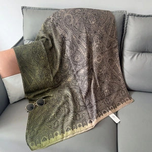 Dettaglio macro della stampa paisley su scialle in cotone e lino verde oliva sul divano