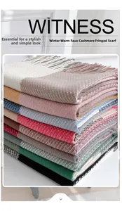 Dettaglio di sciarpe invernali impilate effetto cashmere con frange e vari motivi colorati