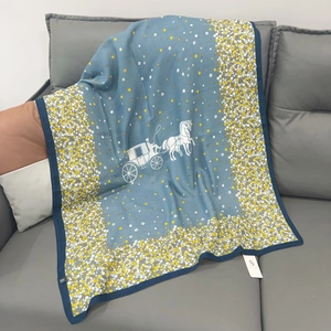 Detailed macro view of blue scarf with carriage logo and floral pattern on sofa