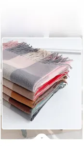 Stack of thick plaid scarves with long tassels showing various colors and wool-like texture