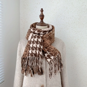 Detail of houndstooth and leopard print scarf with tassels on a beige coat mannequin