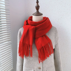 Close-up of the thick red cashmere-like winter scarf with elegant long tassels details