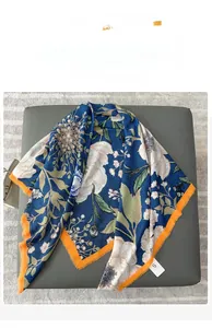 Detail eines bedruckten blauen Schals mit Blumenmustern und orangen Fransenrändern