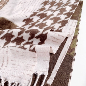 Detailed view of houndstooth cashmere feel scarf with fringe tassels and soft texture
