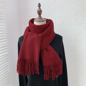 Detail of burgundy fringe scarf in cashmere-like fabric draped over a black coat