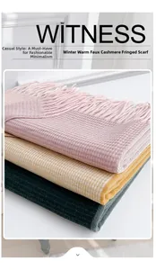 Close-up of fringe details on pink, yellow, and green cashmere-like woven scarves