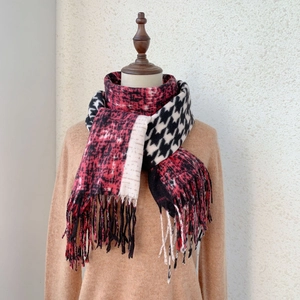 Detail of houndstooth cashmere scarf with tassels and red abstract pattern on mannequin