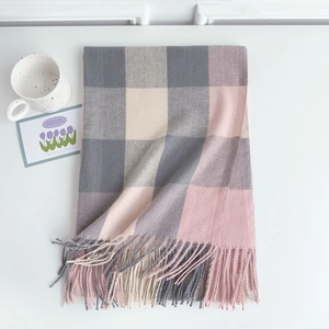 Detail of pink and grey plaid scarf with soft tassels and cozy cashmere-like texture