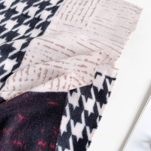 Detail view of houndstooth cashmere scarf with frayed edges and geometric pattern