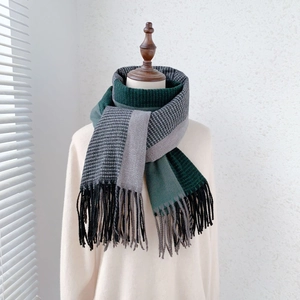 Detail view showing mixed weave patterns and soft fringe trim on a warm bicolor scarf