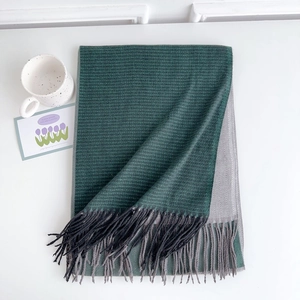 Detail of dark green and grey woven cashmere scarf with fringe and stylish floral decor