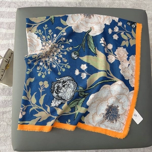 Königsblauer Blumenschal mit orangen Fransen und weißem Druck auf dunklem Lederhintergrund
