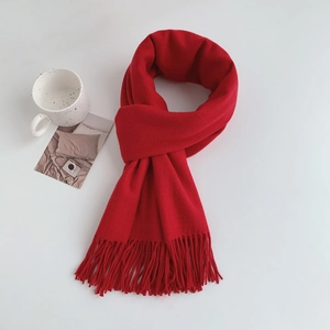 Macro detail of red cashmere-feel winter scarf featuring long decorative fringe tassels