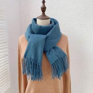Close-up detail of soft peacock blue cashmere-like scarf with fringe tassel decorations