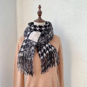 Close-up of houndstooth cashmere-like scarf with long fringe tassels and thick knit texture