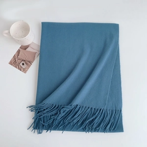 Detail of blue faux cashmere scarf showing soft texture and fringe tassels on a white background