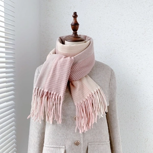 Close-up of pink and white cashmere-like scarf with herringbone pattern and fringe detail