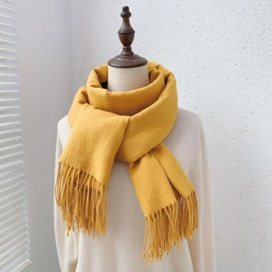 Close-up of ginger yellow knit scarf with long tassels on mannequin display