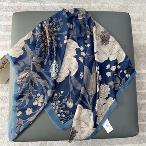 Detail eines marineblauen Schals mit Blumenmuster und Fransen auf einer Lederbank