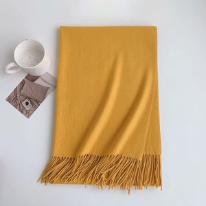 Detail of soft yellow cashmere-like scarf with thick fringe on a clean white background