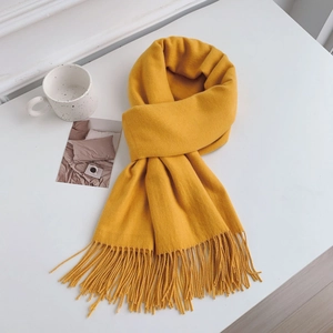 Detail of bright yellow cashmere-like scarf showing soft knit texture and fringe tassels