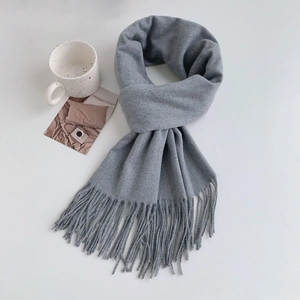 Close-up of light grey cashmere-like scarf with long tassels and winter decor