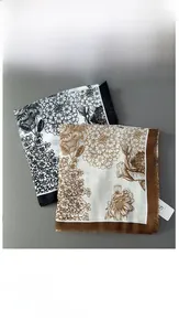 Detailed view of floral print scarves with fine fringe edges in black and white tones