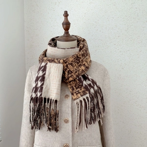 Detail of cashmere-like scarf with leopard print, houndstooth patterns and fringe edges