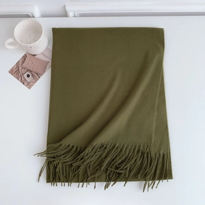 Detail of moss green cashmere-like scarf showing soft texture and fringe tassels
